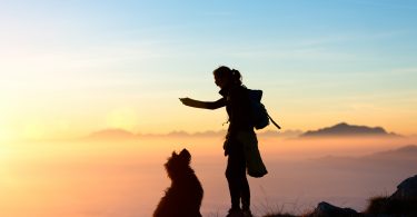 Girl plays with his dog in the mountain